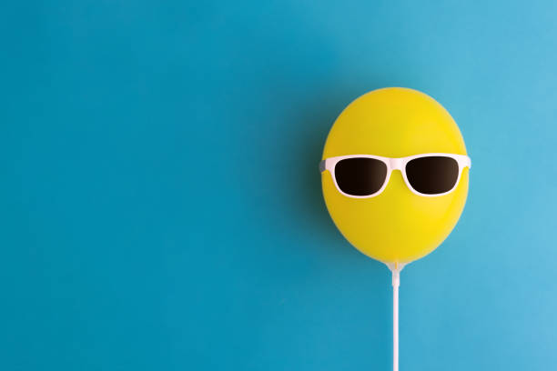 Yellow balloon with sunglasses Yellow party balloon with sunglasses on a blue background offbeat stock pictures, royalty-free photos & images
