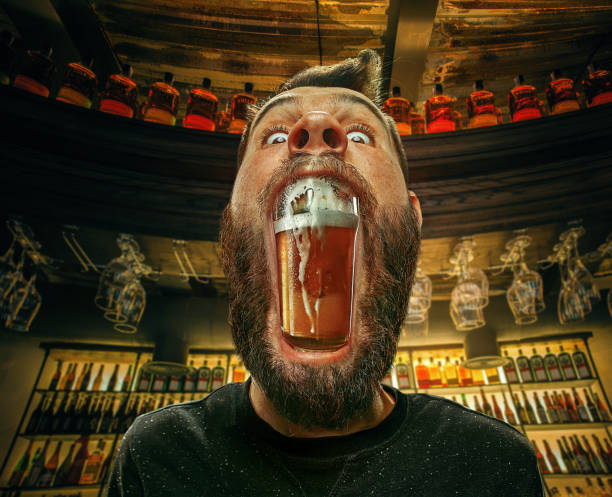 verre de bière dans la bouche de l’homme au bar - grande bouche photos et images de collection