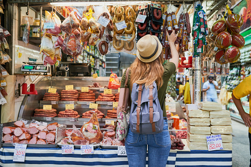 Rearview shot of an unrecognizable woman standing next to a market stall while browsing through the items on display
