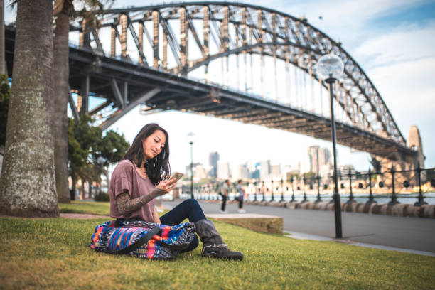 istock Woman using mobile phone  and sitting on grass in Sydney 924955408