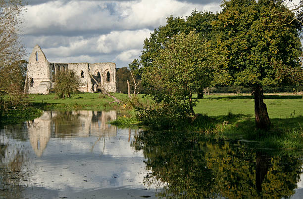 Kirkham Priory, Yorkshire, UK. March 20, 2020.  The banks of the River Derwent with ruins of an ancient abbey on the left bank and woodland on the other.  A cloudy sky is above.