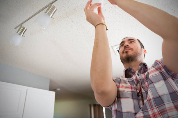 istock Young man installs lighting in his new home 924958260