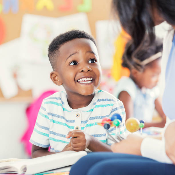 istock Excited preschool age boy studies solar system model with teacher 924958632