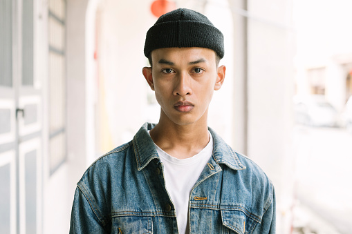 Close up portrait of young asian man wearing a hat, looking at camera