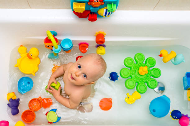 Baby boy taking a bath, playing with colorful toys stock photo