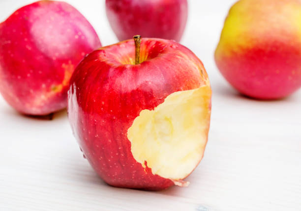 istock Bitten apple on the white wooden table. 924969656