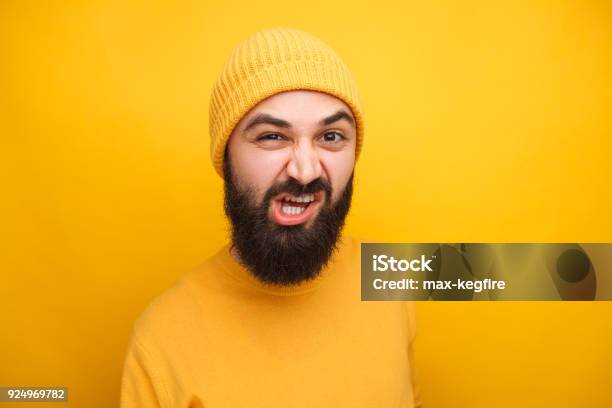 Grimacing Man In Yellow Looking At Camera Stock Photo - Download Image Now - Adult, Adults Only, Aggression