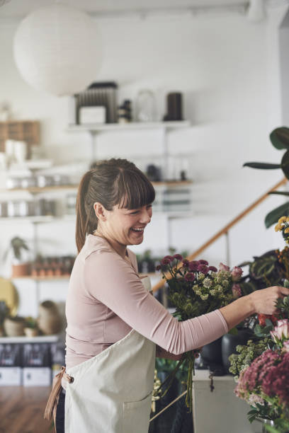 istock Laughing florist arranging a floral display in her shop 924972044