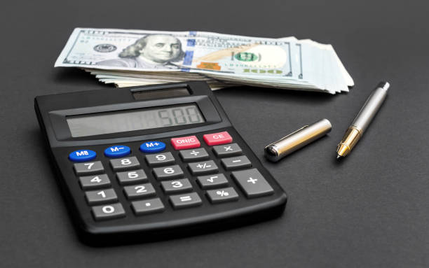 istock Calculator with dollar bills and pen on black. 924973946