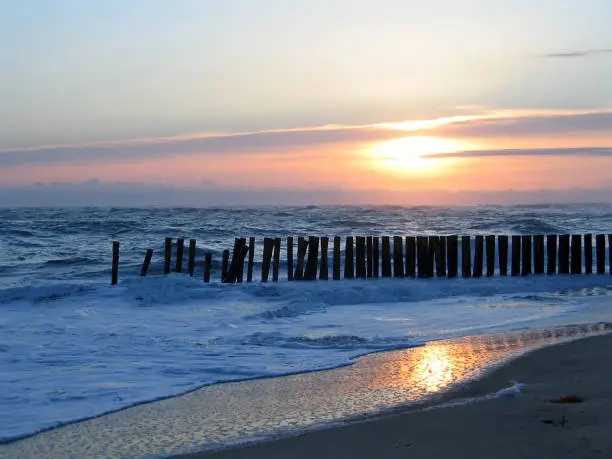 wonderful sunset on wooden wave-breaks on the coast of the atlantic ocean