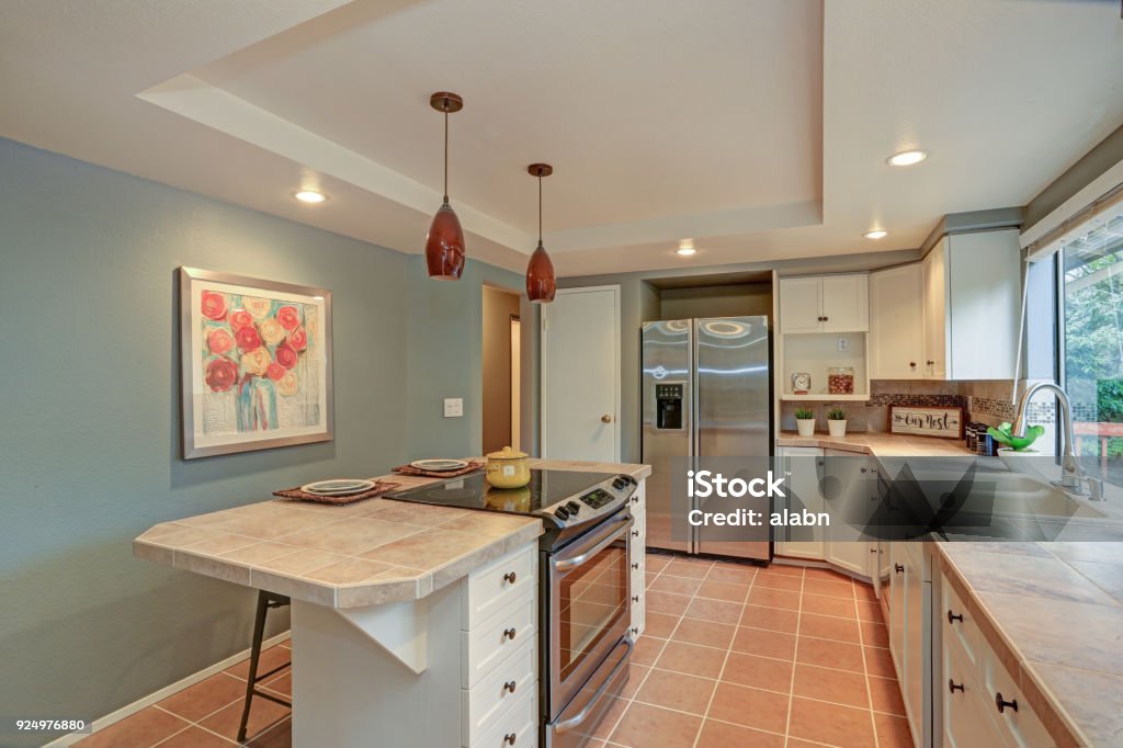 Second floor Kitchen boasts tray ceiling, island Second floor Kitchen boasts tray ceiling, island and white shaker cabinets. Fresh natural colors create cozy atmosphere. Apartment Stock Photo