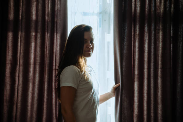 istock woman stand near window in sunlight 924978570