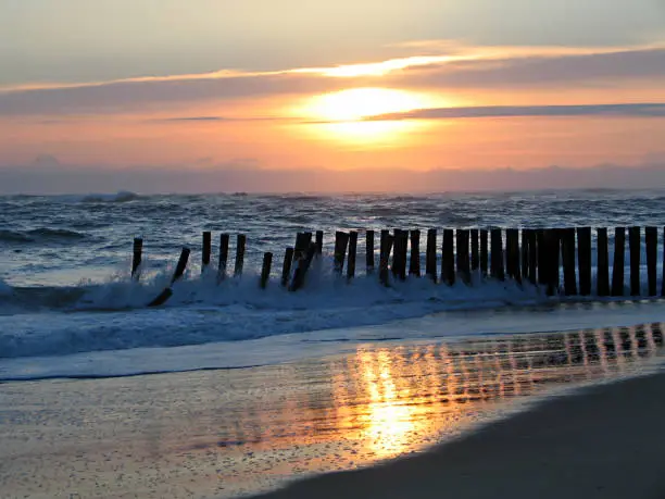 wonderful sunset on wooden wave-breaks on the coast of the atlantic ocean