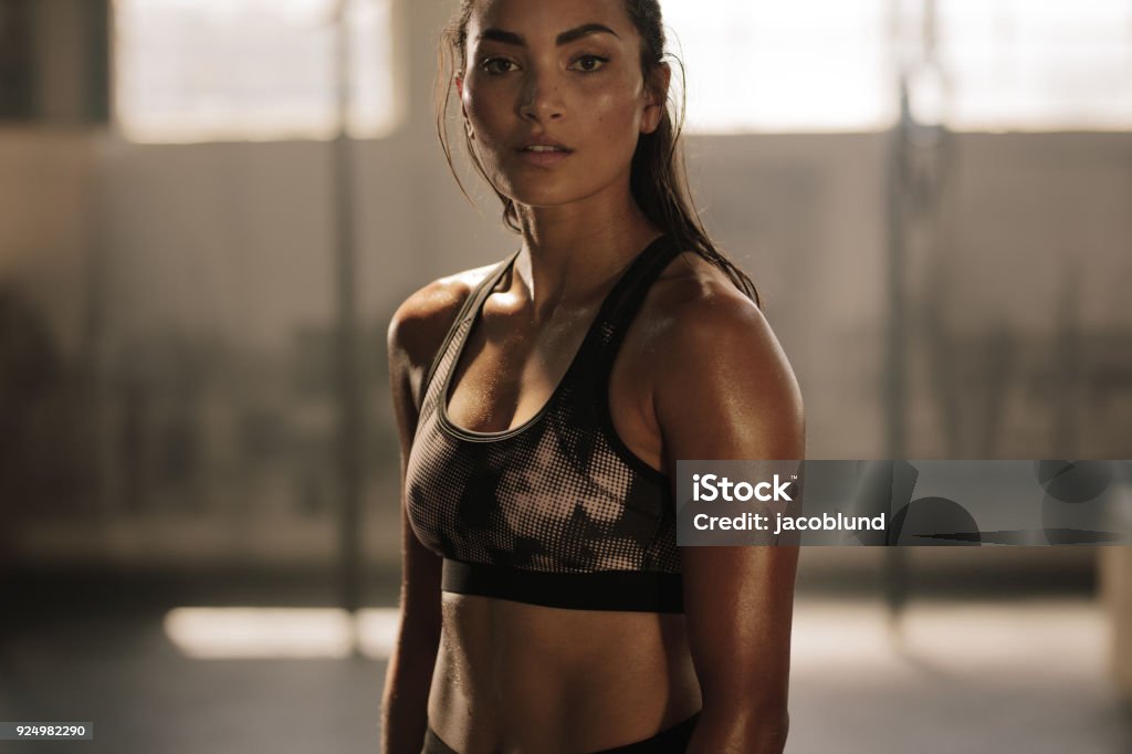 Sportswoman after intense crossing training session Strong and determined female in sportswear standing in the gym and looking at camera. Sportswoman after intense crossing training workout session in gym. Women Stock Photo