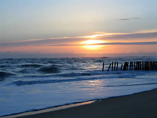 wonderful sunset on wooden wave-breaks on the coast of the atlantic ocean