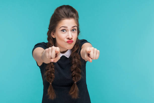 Closeup portrait of crazy woman pointing finger at camera. Closeup portrait of crazy woman pointing finger at camera. Studio shot, blue background face-angles stock pictures, royalty-free photos & images