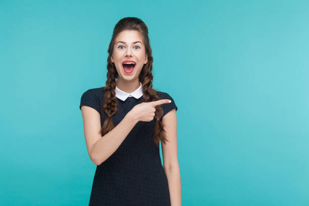 Happiness woman pointing finger at copy space. Happiness woman pointing finger at copy space. Studio shot, blue background Pigtails stock pictures, royalty-free photos & images