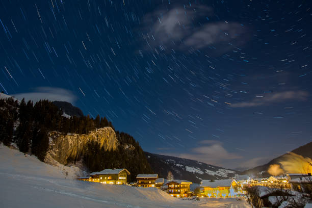 istock Star trails in the sky during a clear winter night over an autrian town 925001426