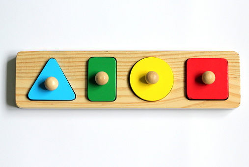 A child's wooden shape sorter puzzle with a triangle, circle, square and rectangle