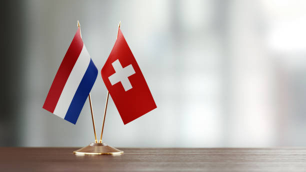 istock Dutch And Swiss Flag Pair On A Desk Over Defocused Background 925030162