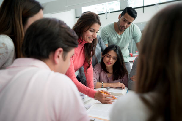 istock Beautiful mentor of college students explaining to a group the homework at the library and everyone paying attention 925033402