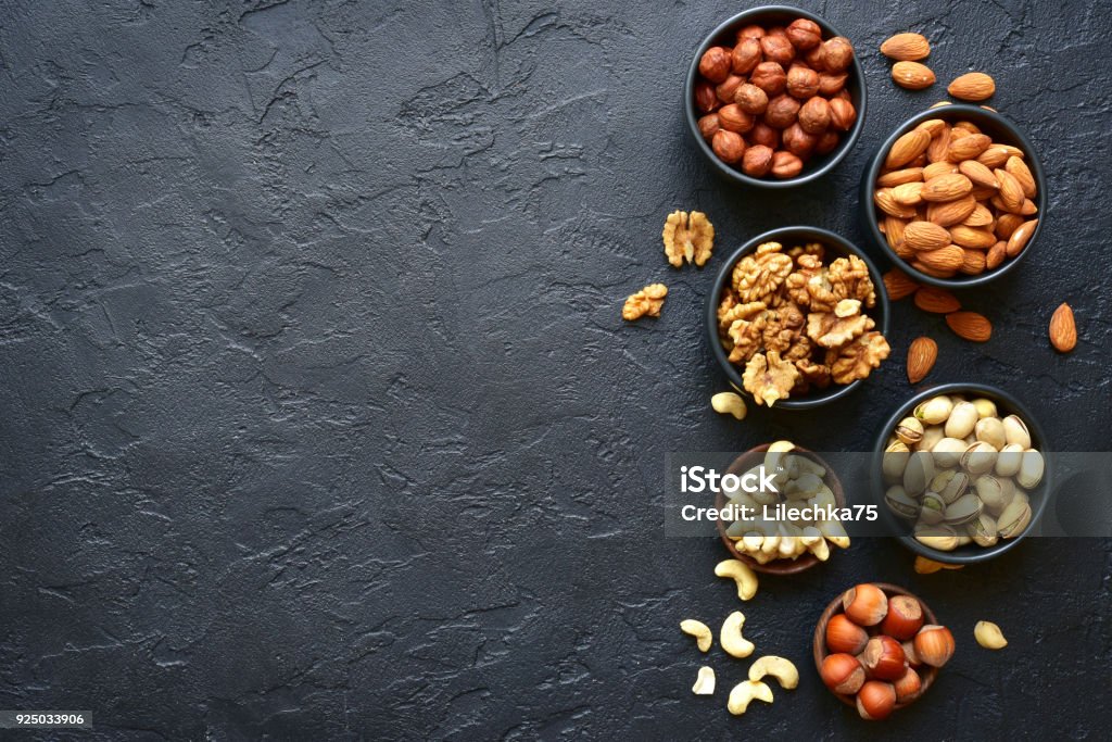 Assortment of nuts on  a black slate or stone background Assortment of nuts on  a black slate or stone background - healthy snack.Top view with copy space. Nut - Food Stock Photo