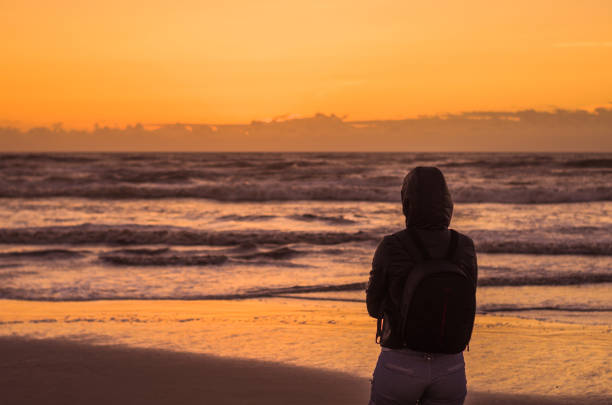 Woman looking at the horizon, beach at sunset