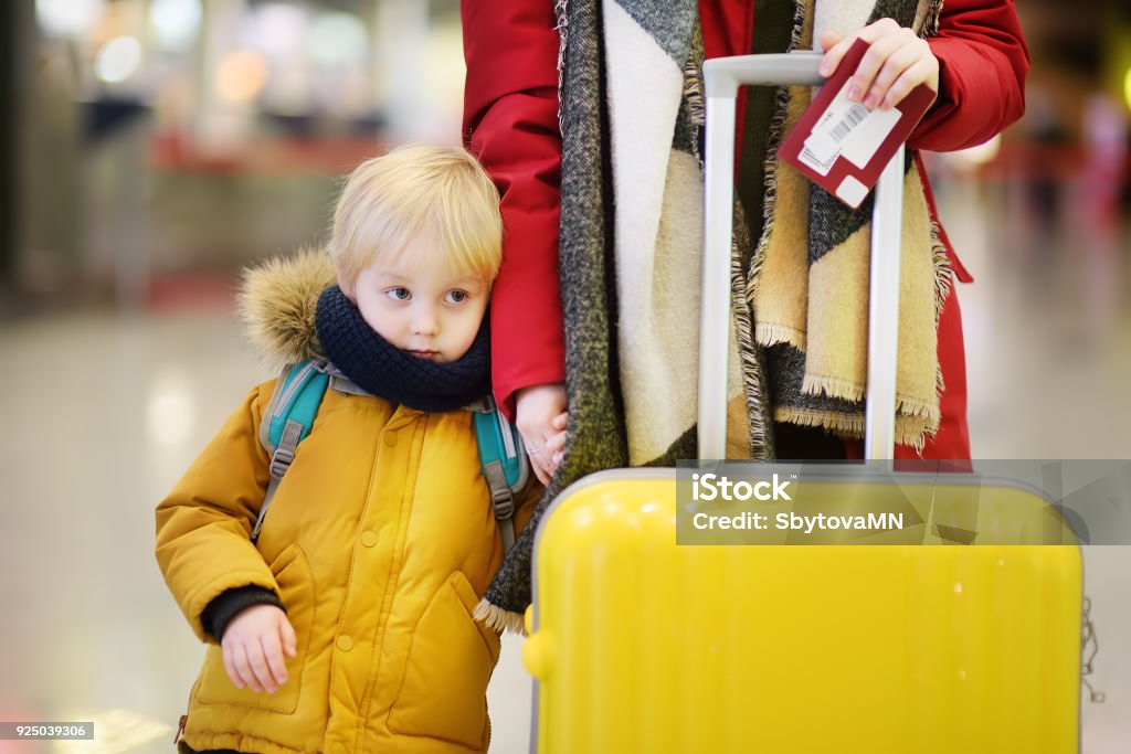 Close-up photo of woman with little boy at the international airport Close-up photo of woman with little boy at the international airport. Mother holding hands with her cute little son. Family travel or immigration concept Vacations Stock Photo
