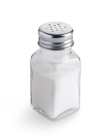 Salt shaker with salt on green background.