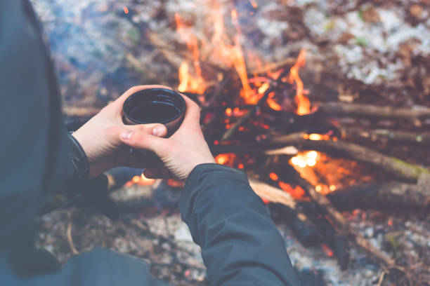 istock Man hands holding cup of tea near the fire 925046918