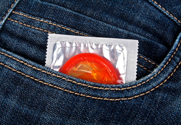 préservatifs colorés dans une poche de jeans bleu - sex condom jeans horizontal photos et images de collection