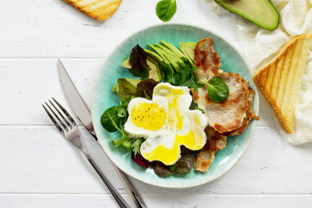 istock English breakfast - fried egg, fried bacon, spinach, arugula, avocado, toast and orange juice. Top view with copy space. 925048360