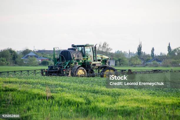 Tractor With A Spray Device For Finely Dispersed Fertilizer Tractor On The Sunset Background Tractor With High Wheels Is Making Fertilizer On Young Wheat The Use Of Finely Dispersed Spray Chemicals Stock Photo - Download Image Now