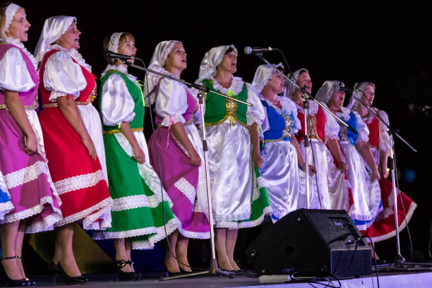 Ponte de Lima, Portugal - May 15, 2016: Folklore dancers singing and dancing on a platform at the riverside in Ponte de Lima, the band with instruments seen behind and spectators on the left. This outdoor platform for festivals and performances on market day.
