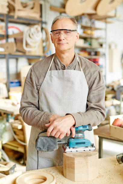 istock Satisfied mature carpenter with sander 925063068