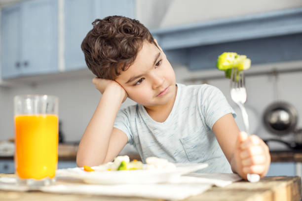 istock Sad boy looking at the green vegetable on his fork 925064512