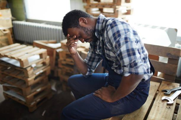 épuisement des africain employé dans l’entrepôt - tired men african descent sadness photos et images de collection