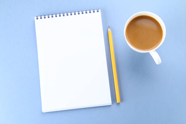 istock Top view image of open notebook with blank pages and coffee on blue background, ready for adding or mock up. Still life, business, office supplies or education concept. 925079836