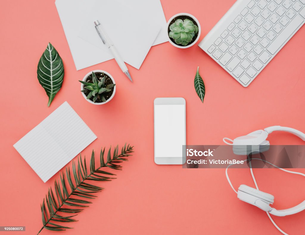 Mockup of smartphone with white screen on pastel background. Flat lay, top view workspace Table Stock Photo