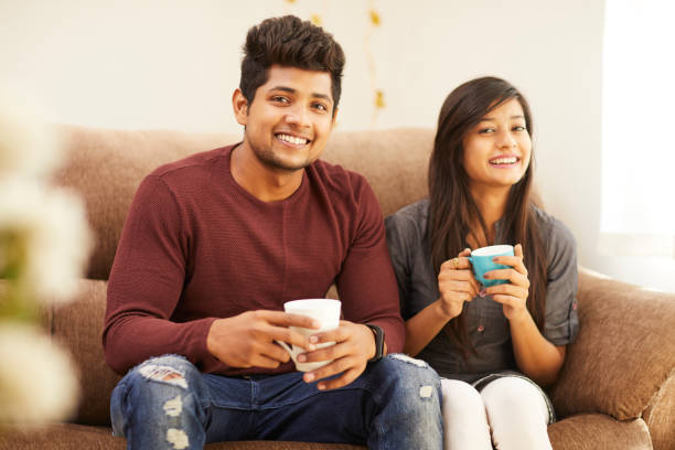 istock Cheerful young beautiful couple having coffee together on sofa 925083682