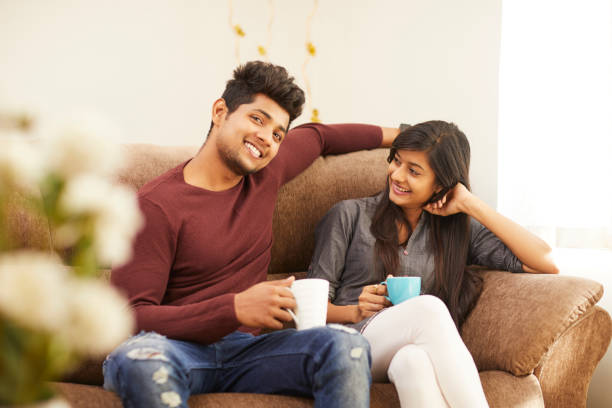 istock Cheerful young beautiful couple having coffee together on sofa 925083690