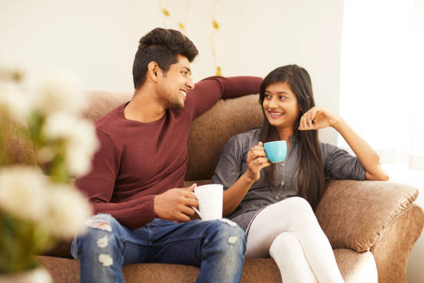 istock Cheerful young beautiful couple having coffee together on sofa 925083710