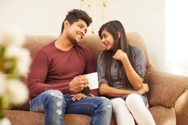 istock Cheerful young beautiful couple having coffee together on sofa 925083720