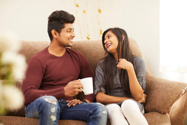 istock Cheerful young beautiful couple having coffee together on sofa 925083726