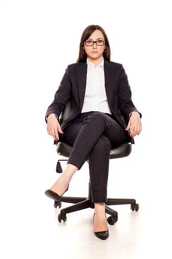 Serious businesswoman in armchair posing on white background