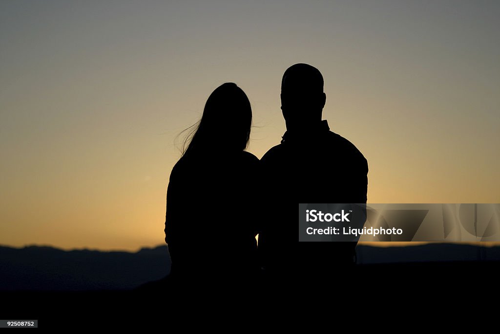 Silhouette di coppia al tramonto - Foto stock royalty-free di Accudire