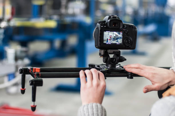 Videographer using camera slider, making video of business at factory
