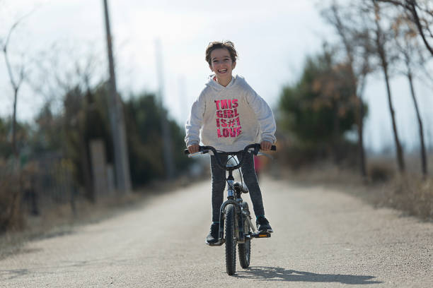 petite fille va avec son vélo vers la caméra en souriant. - ten speed bicycle photos et images de collection