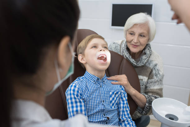 istock Dentist examining teeth of boy supported by granny 925097198