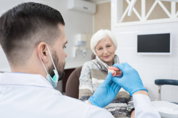 istock Prosthodontist showing new denture to elderly patient 925097614